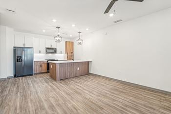 a kitchen and living room with wood flooring and a stainless steel refrigerator at The Maddox Luxury Apartment Homes, Buckeye, 85326